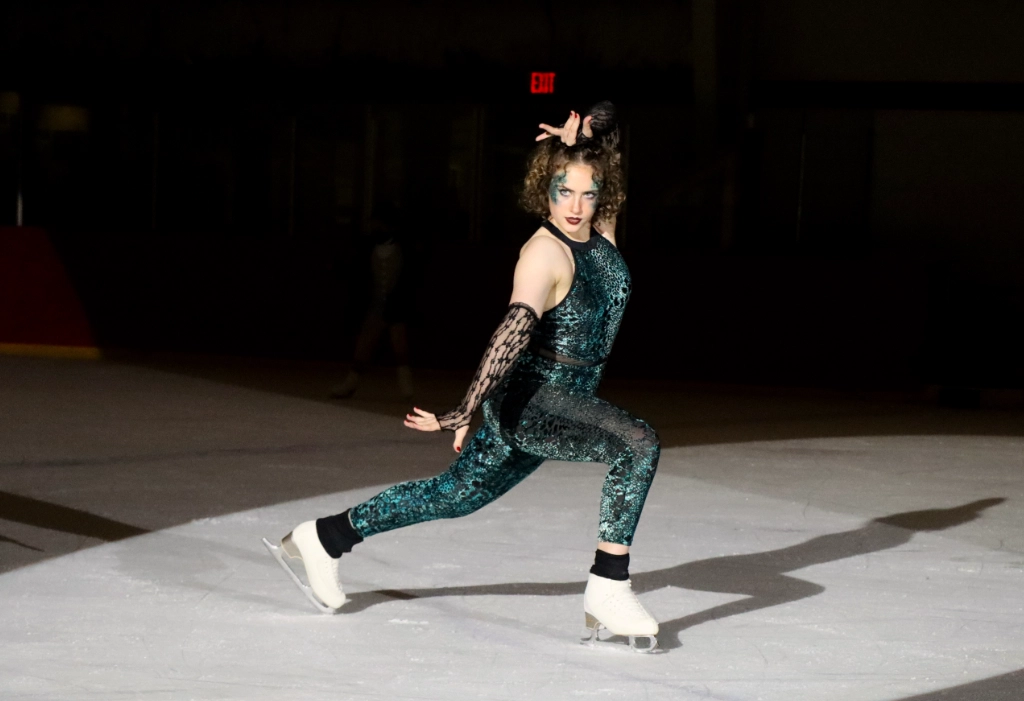 Lunging skater in velvet green leotard posted with arms outstretched